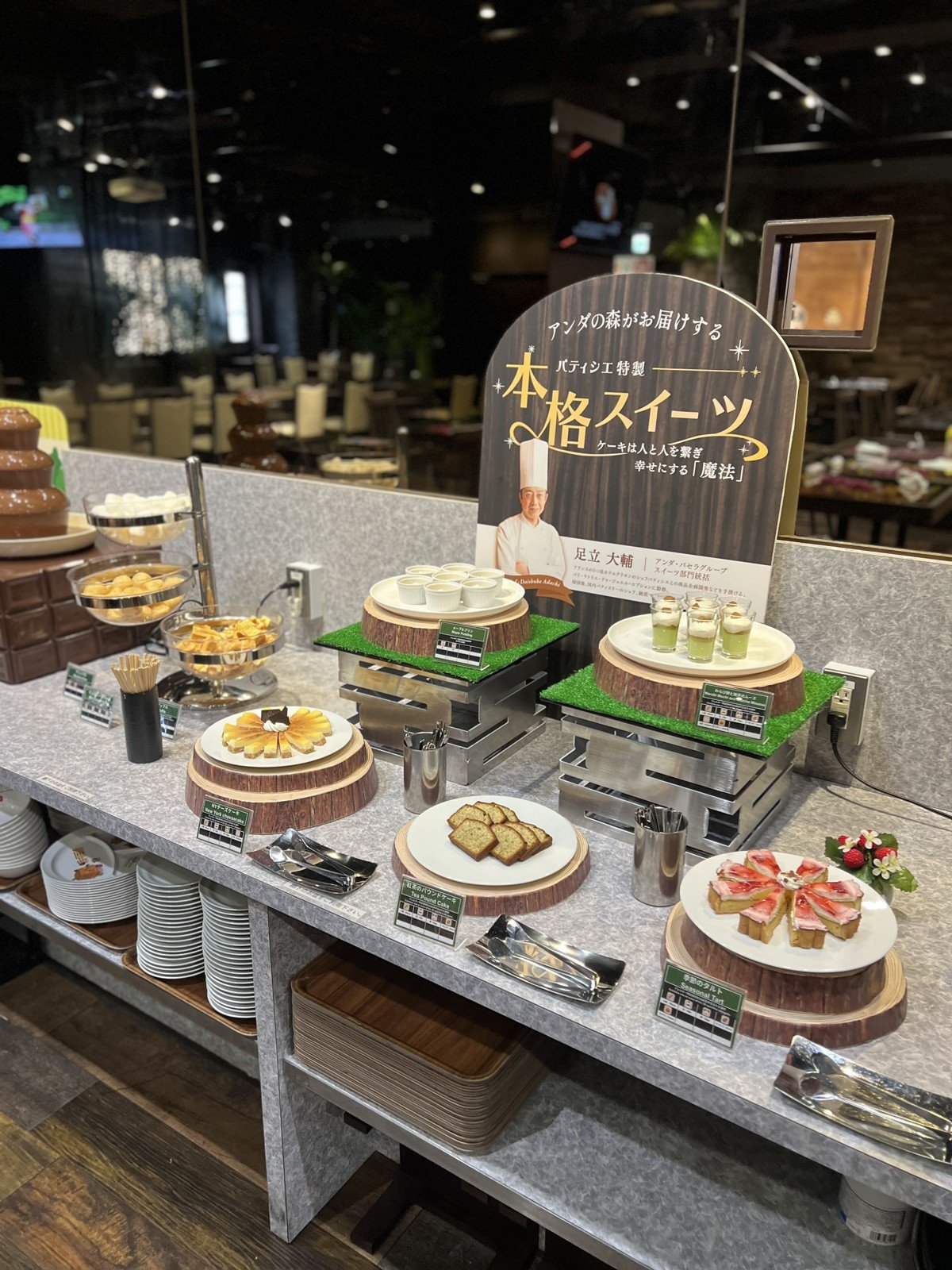 「パティシエ特製 本格スイーツ」の看板と、チーズケーキやタルトが並ぶスイーツコーナー