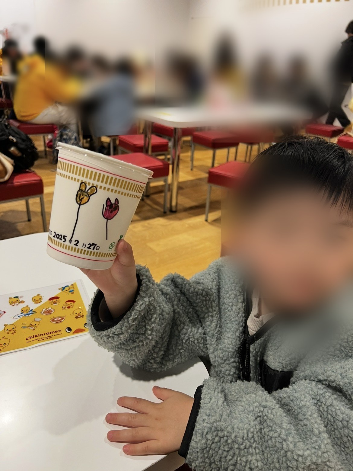 できあがったカップを持ち上げて見せる子ども