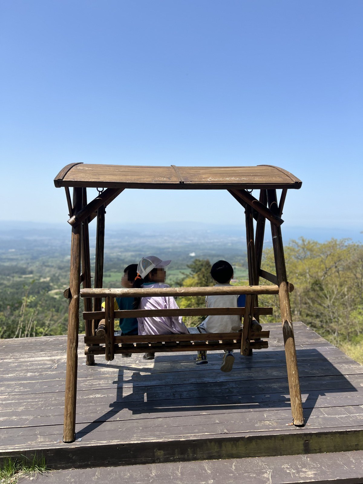 屋根つきのブランコに座って景色をながめる子どもたち