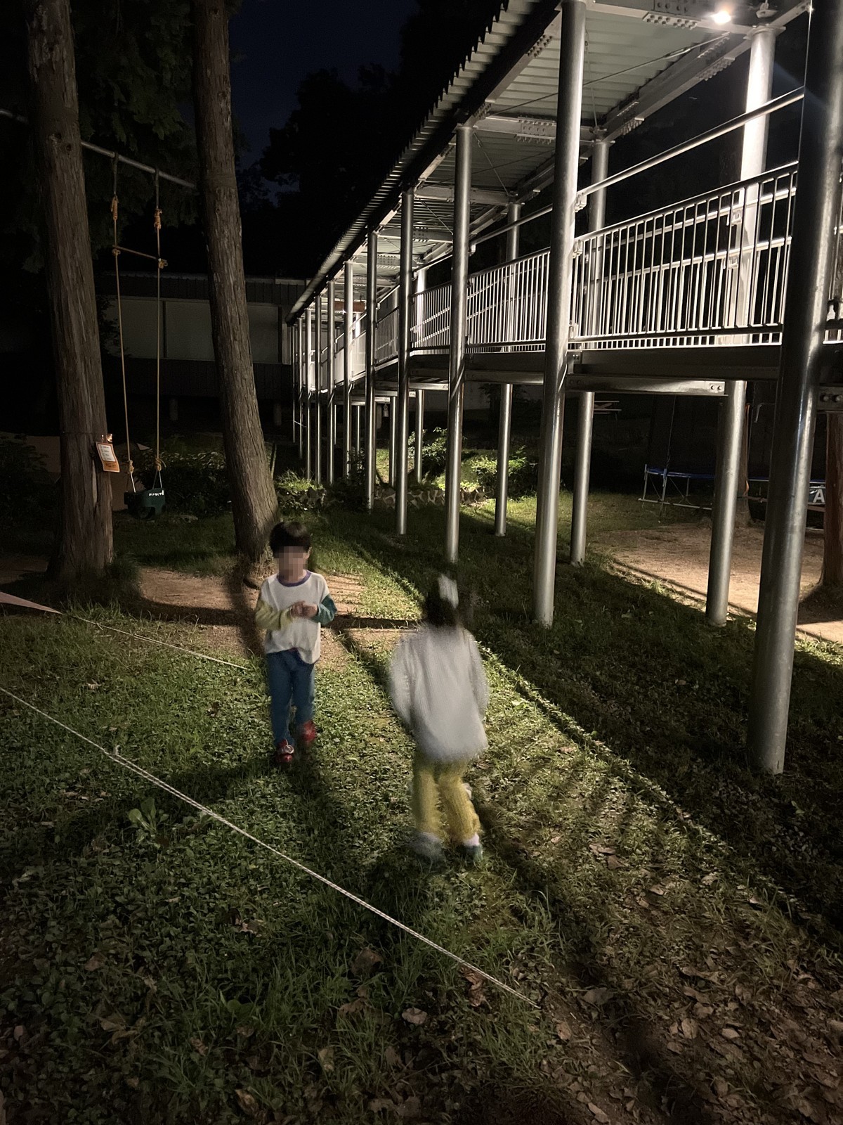 夜、ライトのついた建物のそばで遊ぶ子どもたち