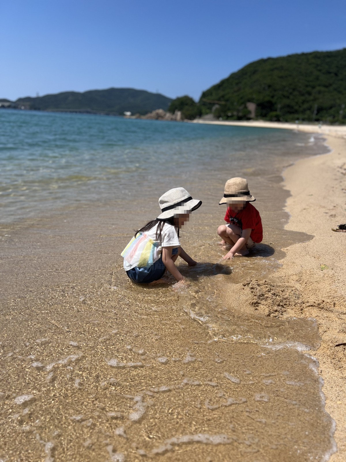 波打ち際で砂遊びをする子どもたち