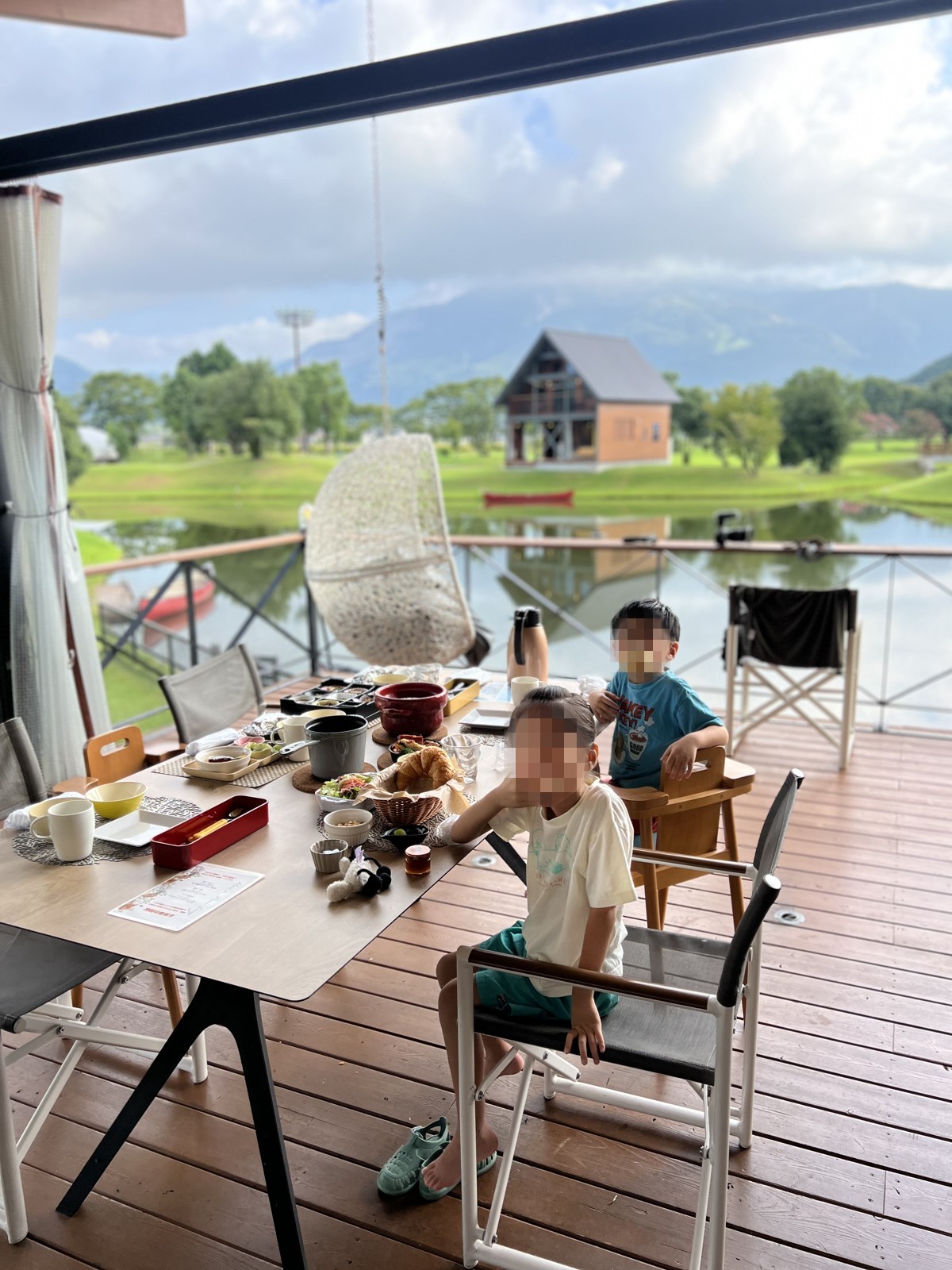 池を望むデッキで朝食を食べる子どもたち