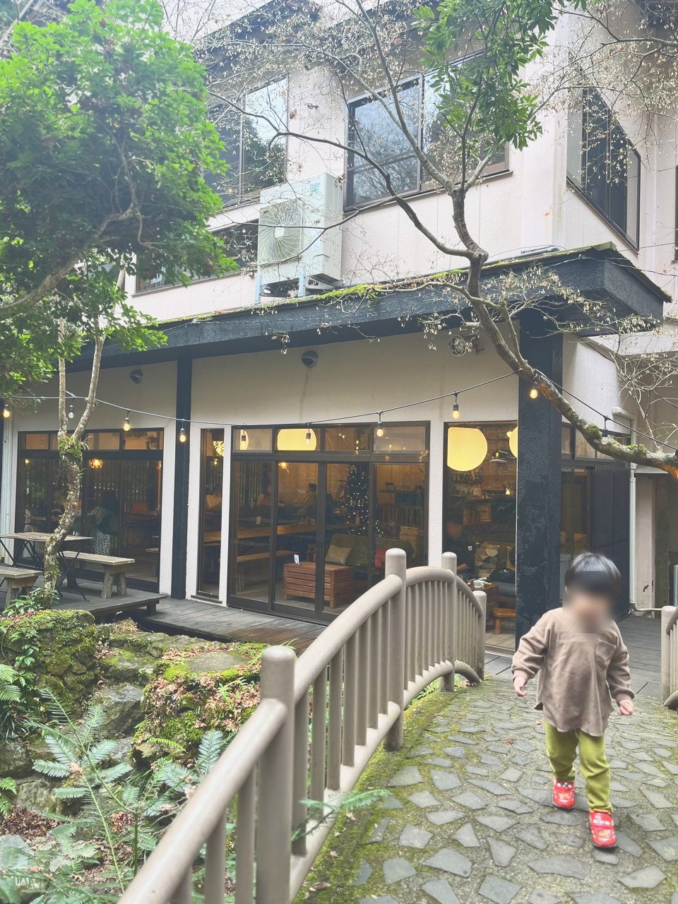庭の小さな橋を歩く子ども。奥にカフェの建物
