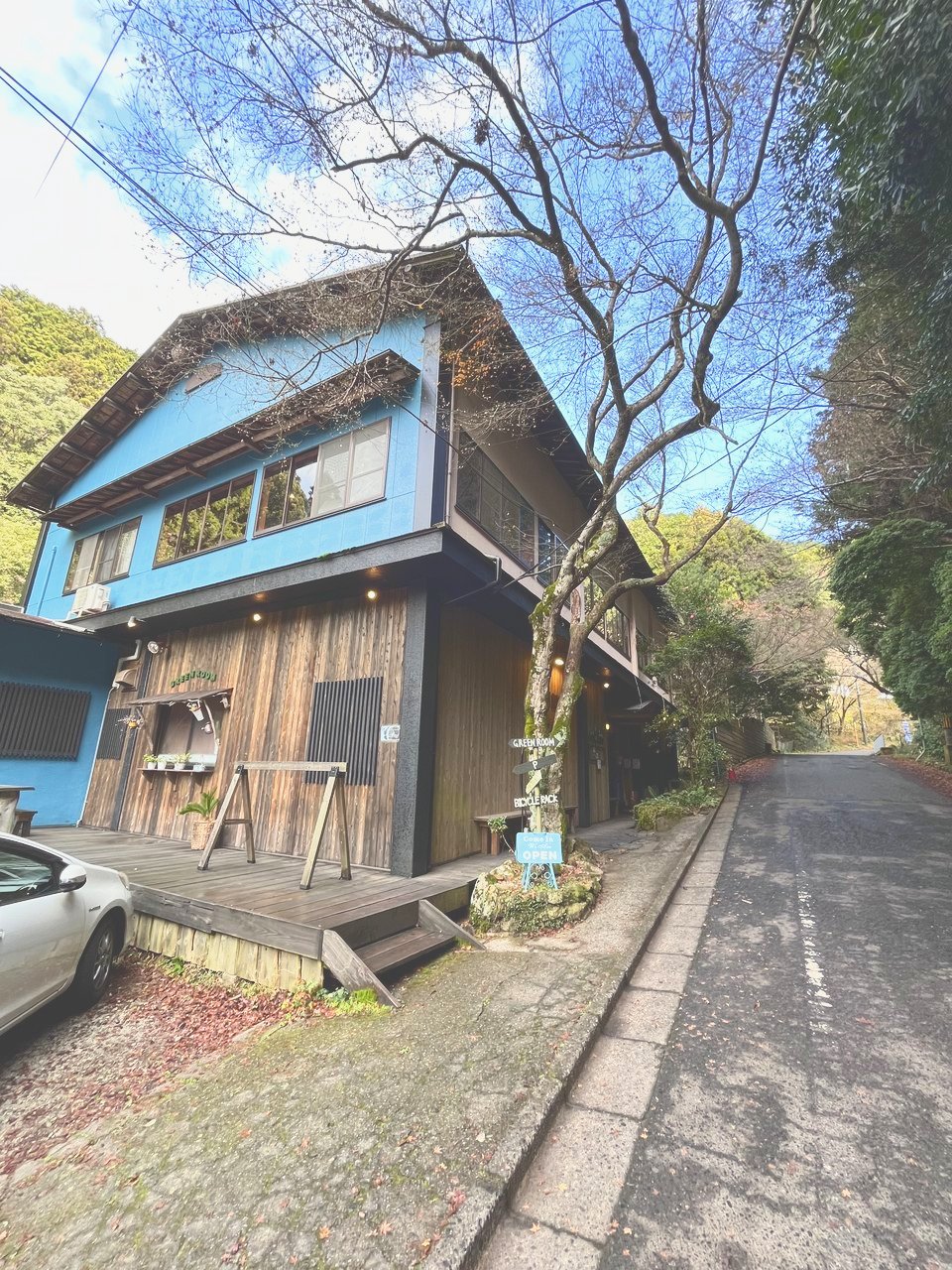 木の外壁に「GREEN ROOM」の文字が入った建物と、横の細い道