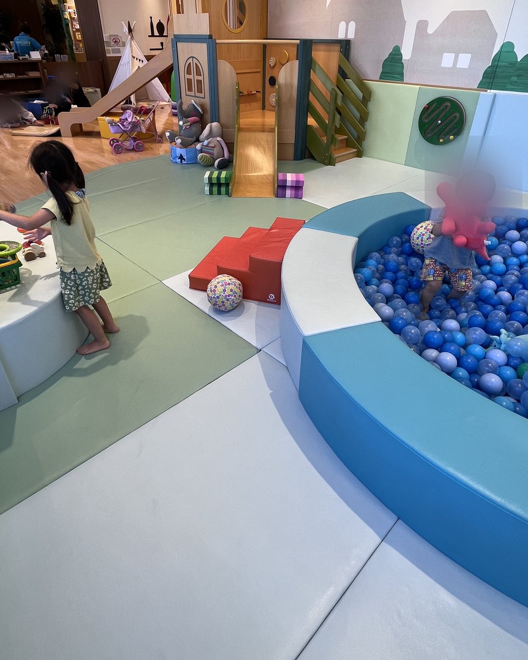 ボールプールの中の子どもと、縁でままごとをする子ども