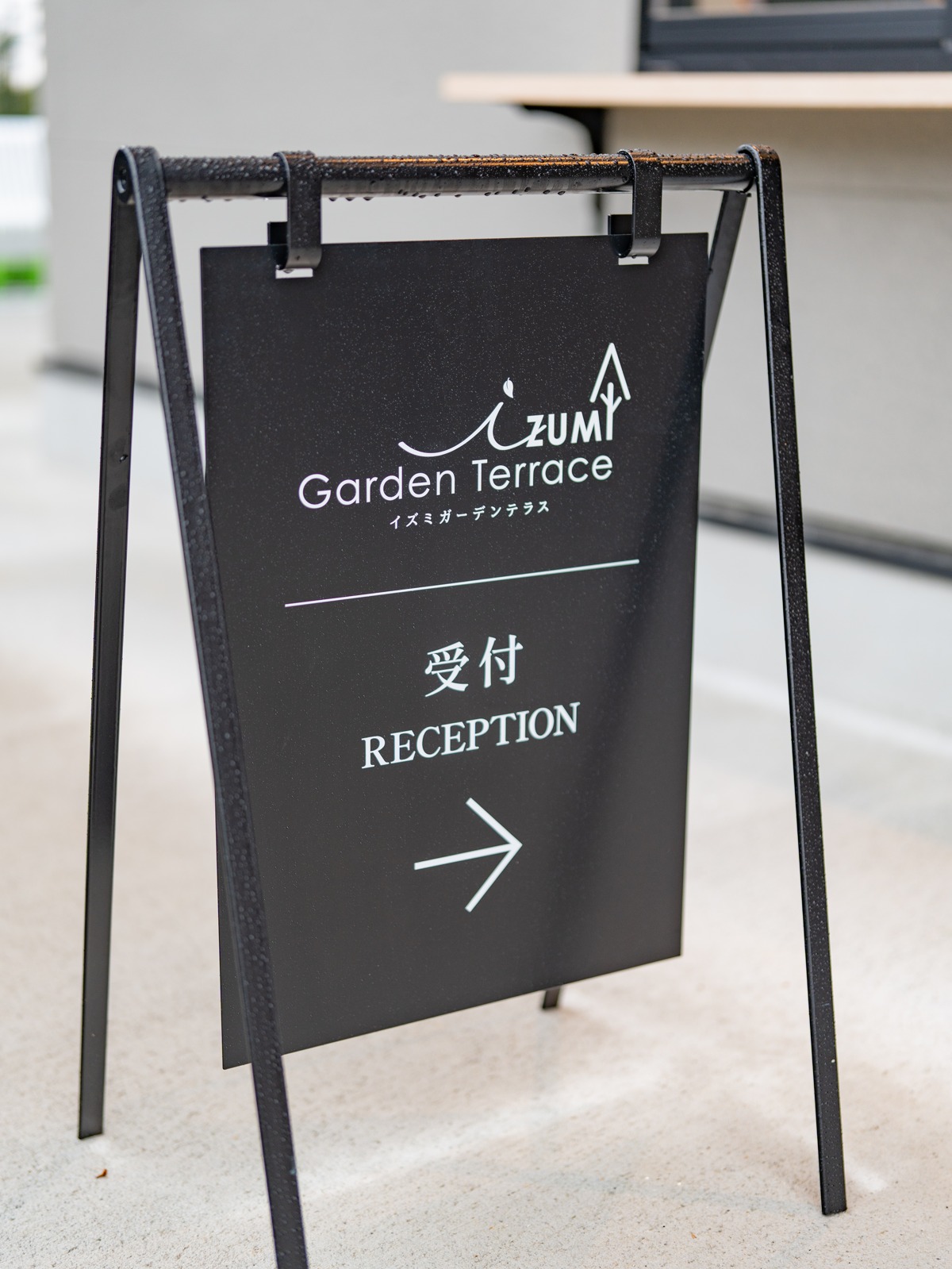 「IZUMI Garden Terrace 受付 RECEPTION →」と書かれた黒い立て看板