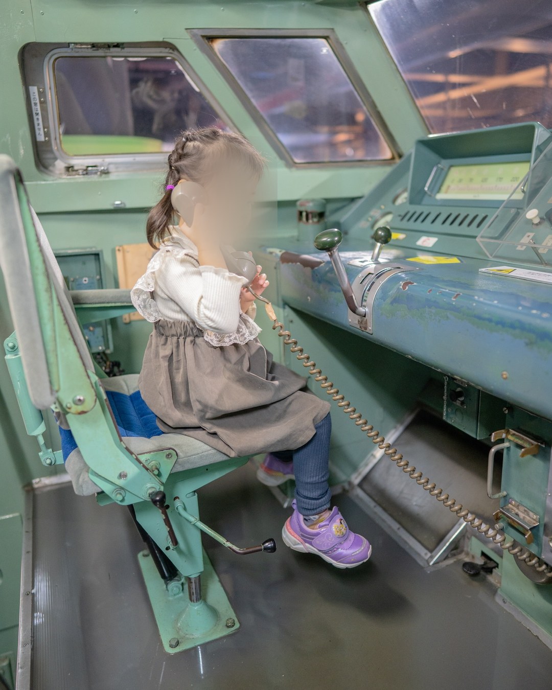運転台に座って受話器を持つ子ども