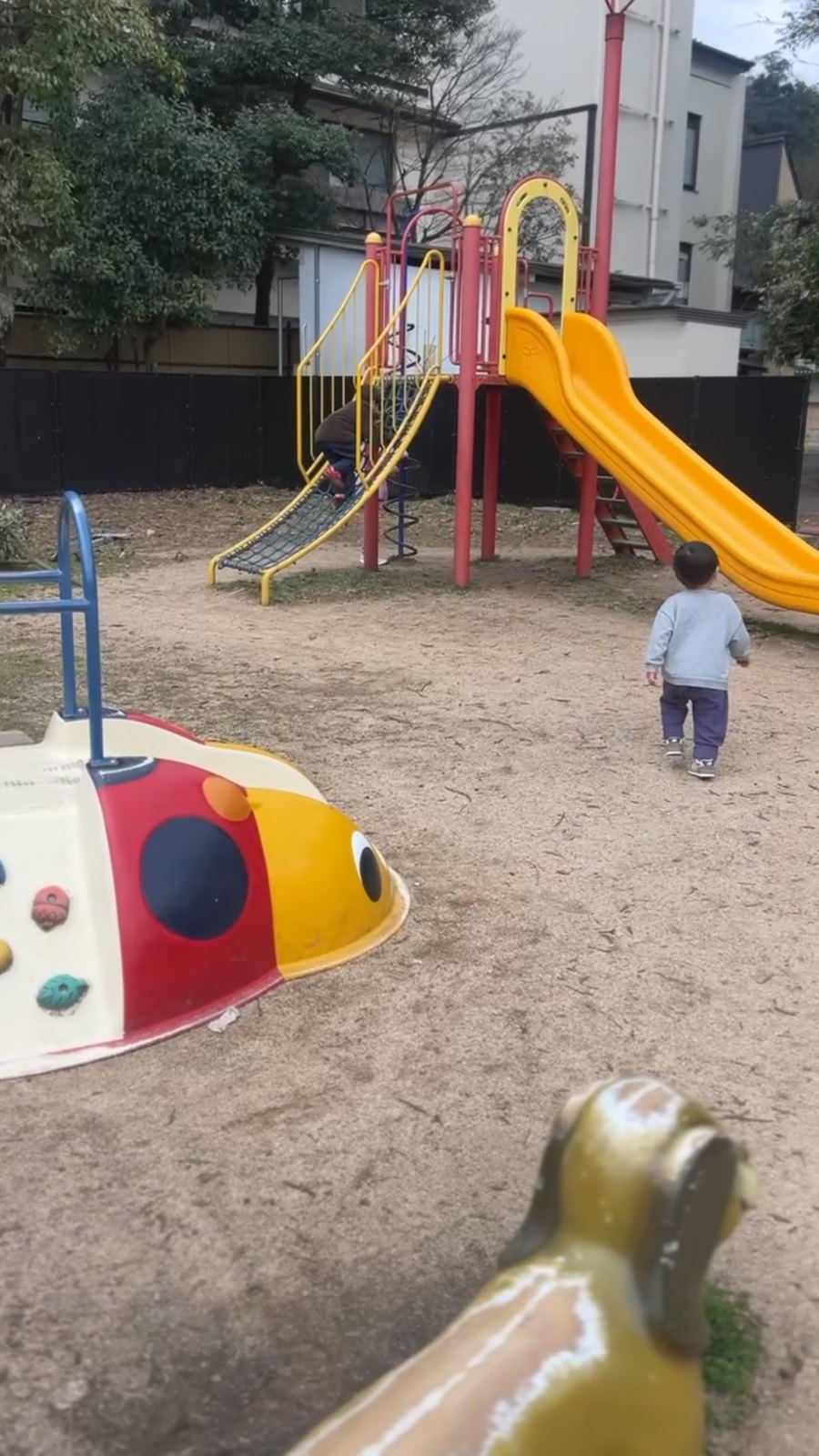 すべり台とてんとう虫の遊具がある小さな公園
