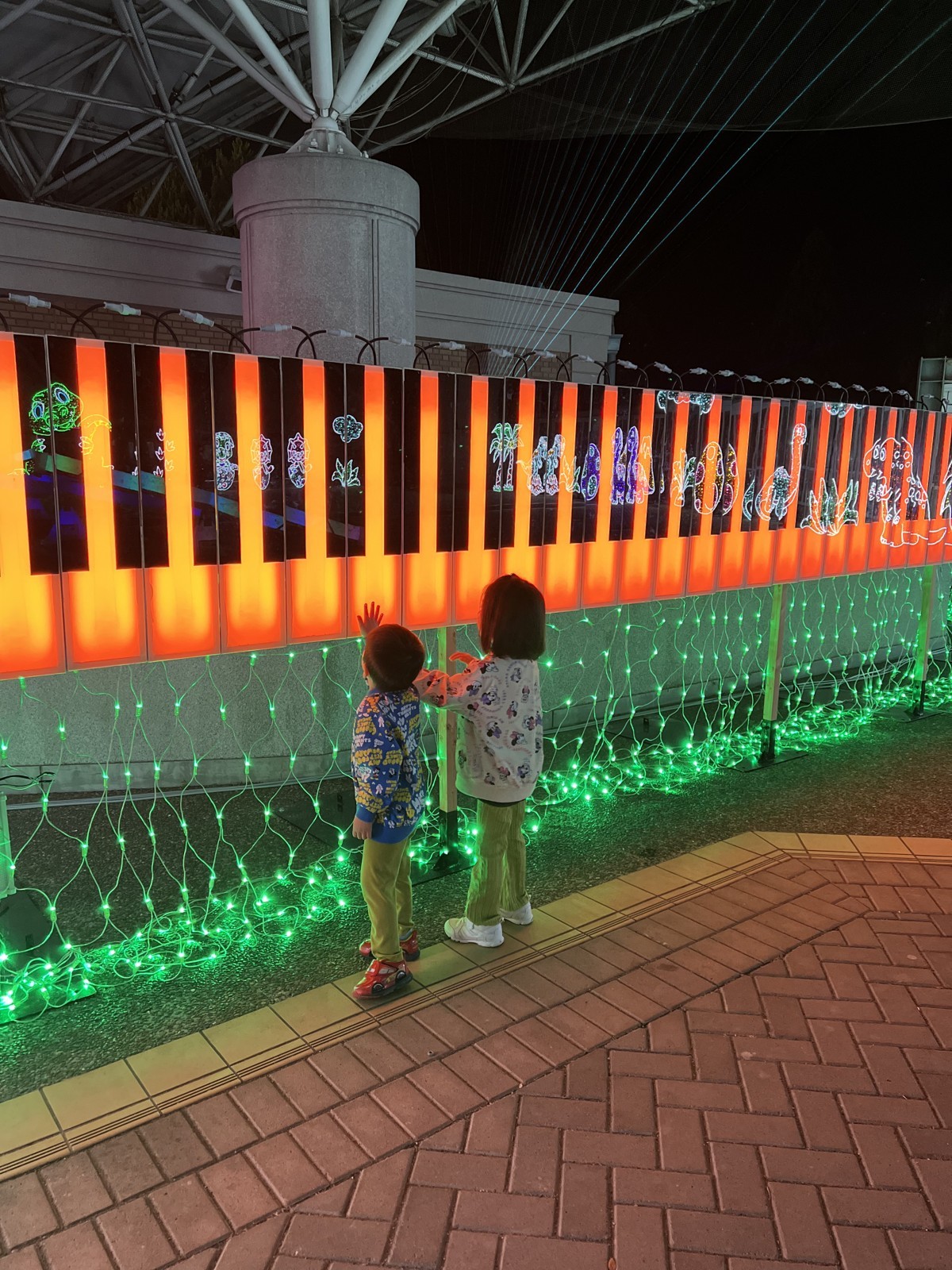 光るピアノの鍵盤を見る子どもたち