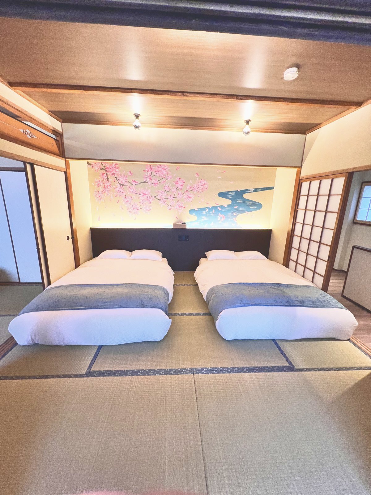 桜の絵が描かれた和室に、畳の上に置かれたベッド2台