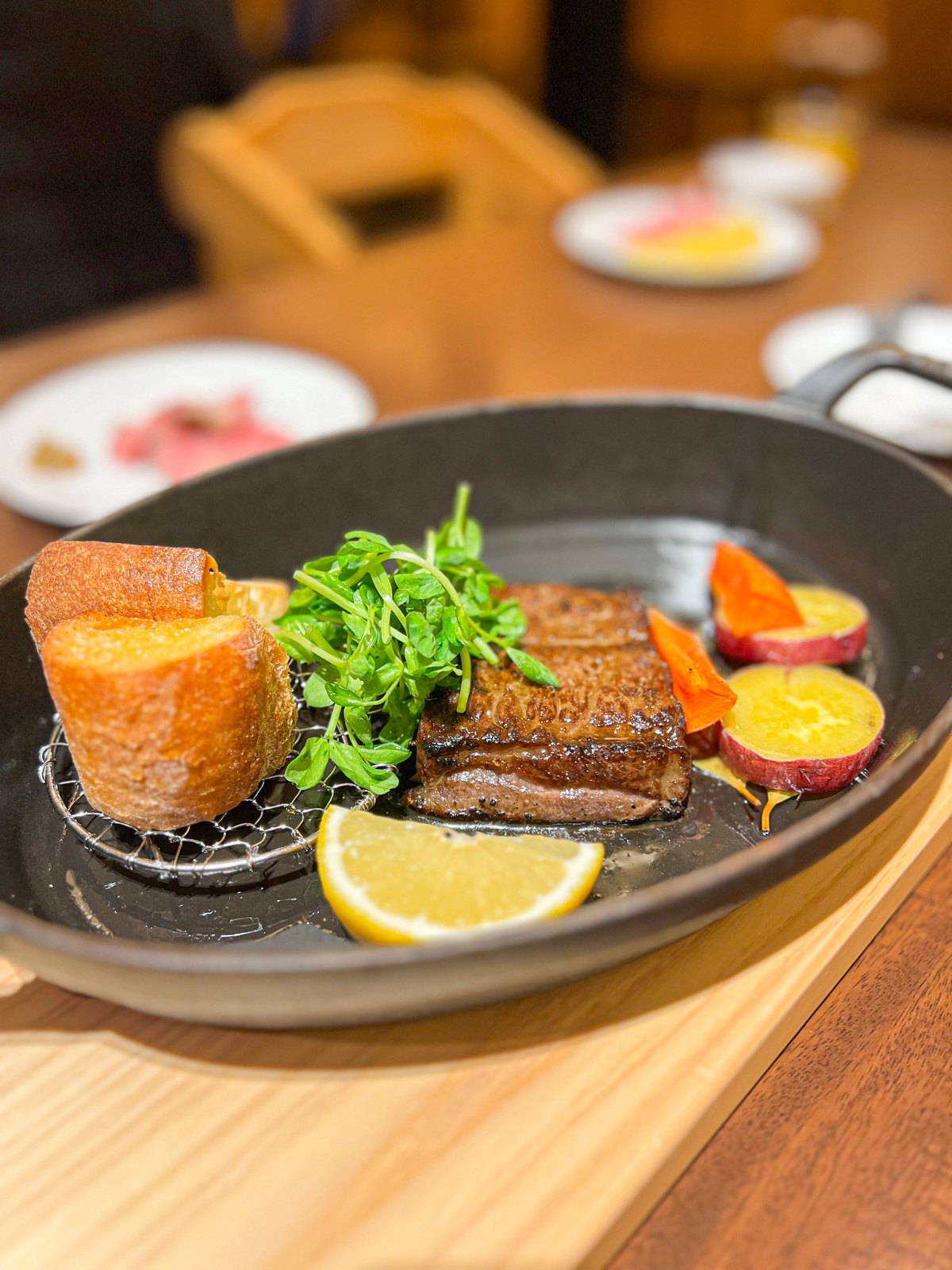スキレットで焼き上げたステーキと、バゲットや野菜の付け合わせ