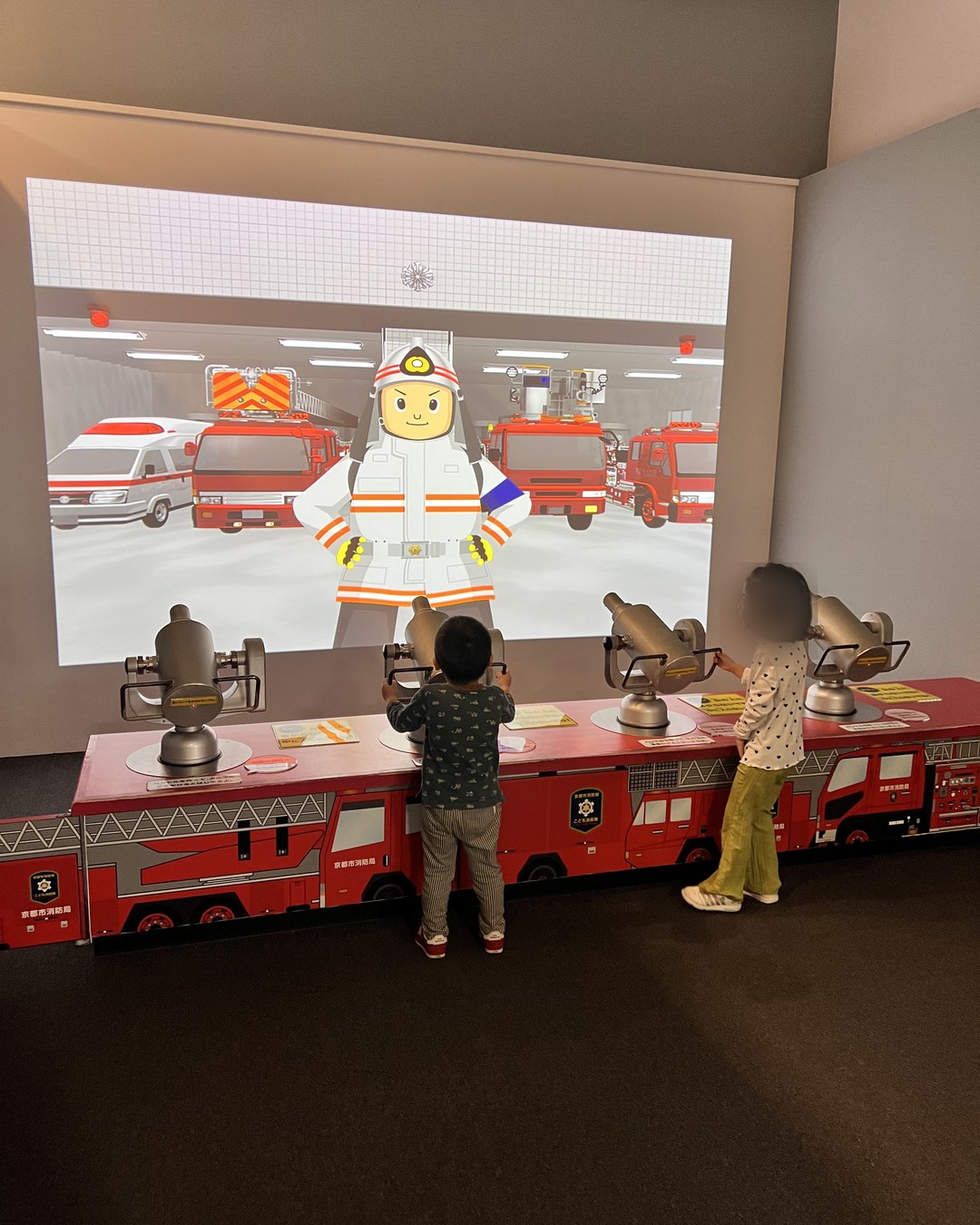 スクリーンに向かって放水ノズルを構える子どもたち
