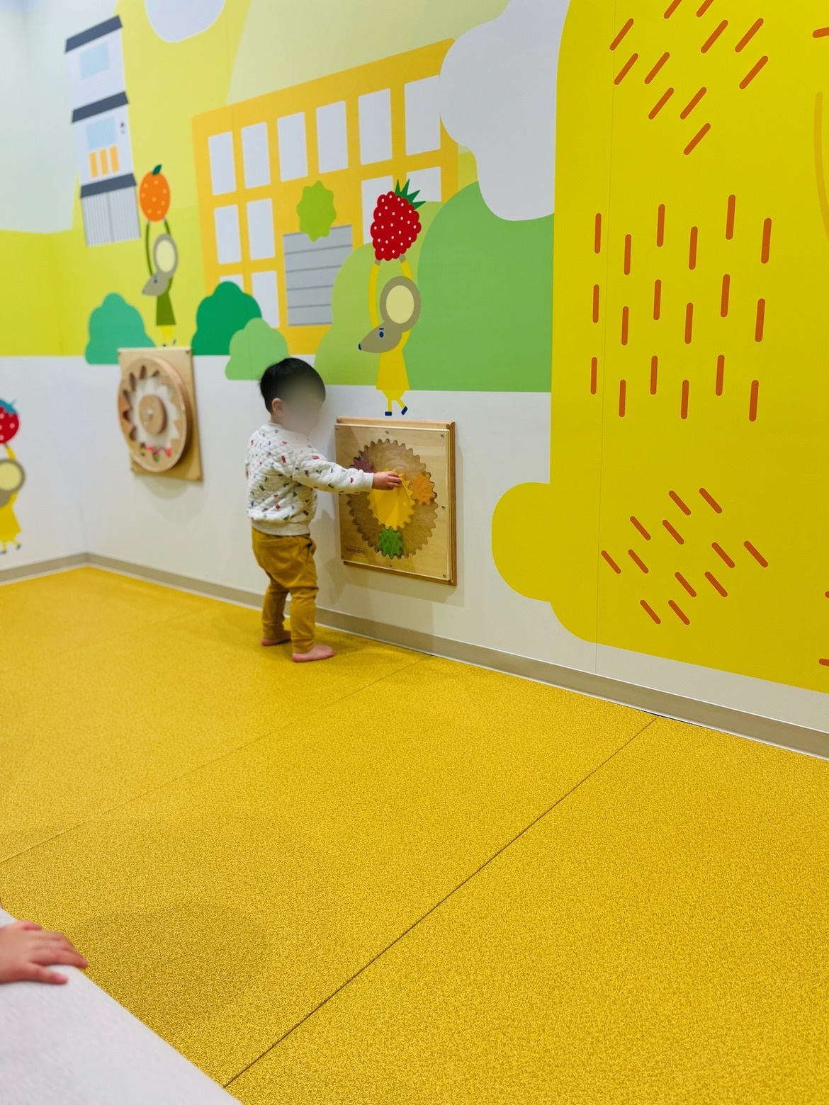 壁のしかけおもちゃで遊ぶ子ども