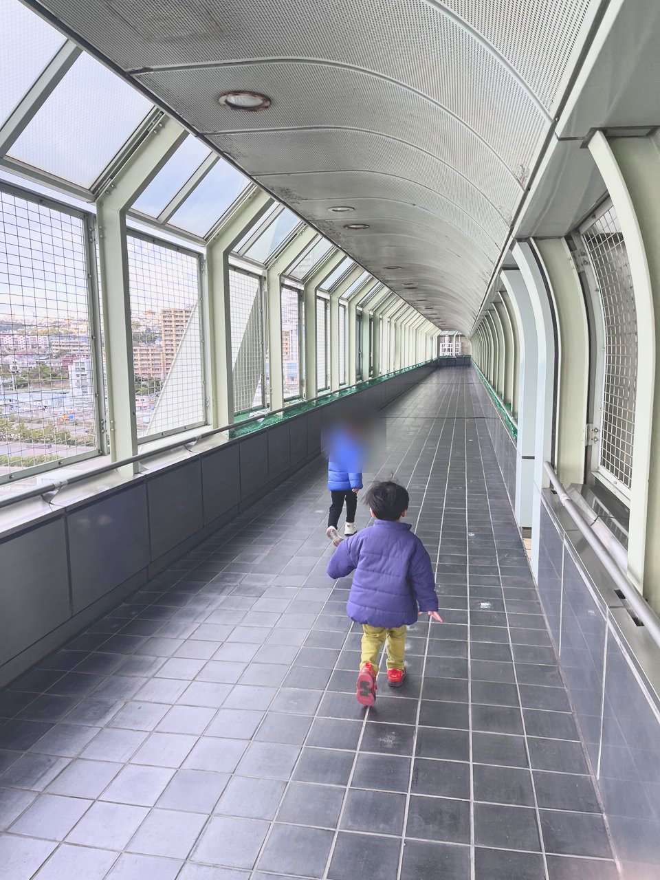 窓が並ぶ長い通路を歩く子どもたち