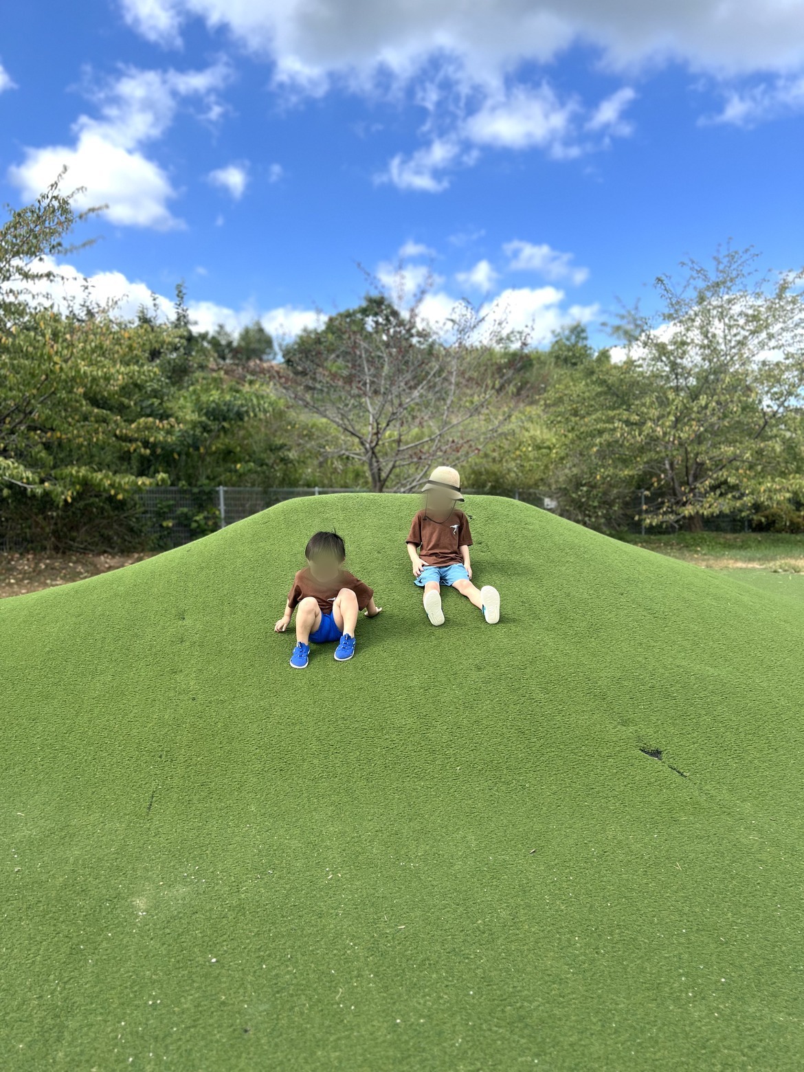 人工芝の丘に座る子どもたち