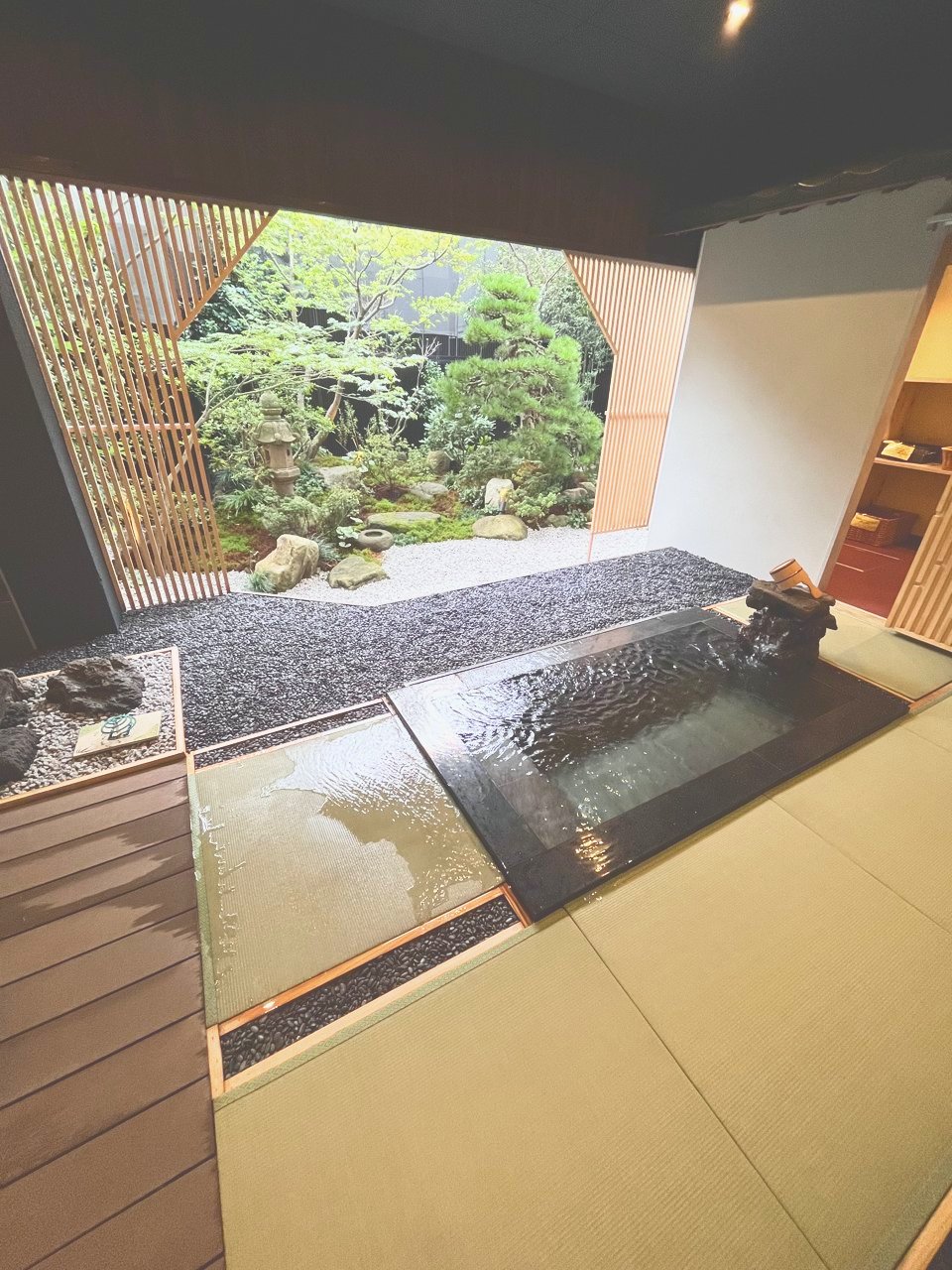 畳の床に湯船があり、その先に庭が見える貸切風呂