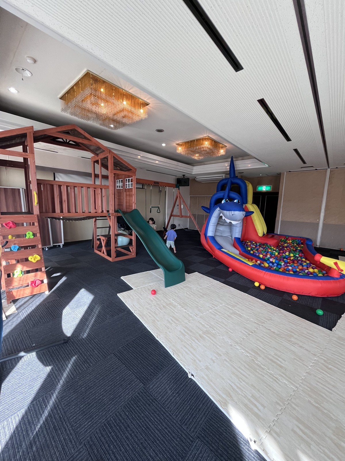 木製の遊具とエアー遊具のボールプールが並ぶキッズスペース