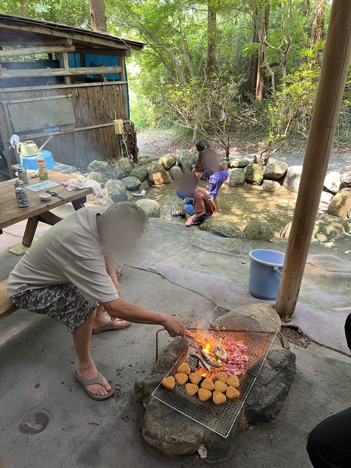 BBQの網で魚やお肉、焼きおにぎりを焼くそばで、子どもたちが池で魚を探す