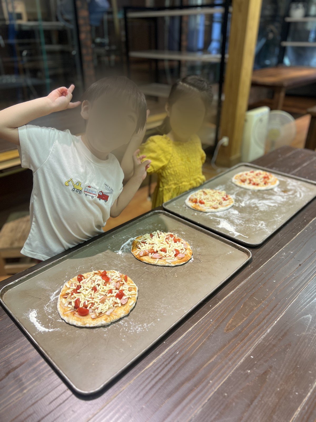 自分でトッピングしたピザを前に、はしゃぐ子どもたち