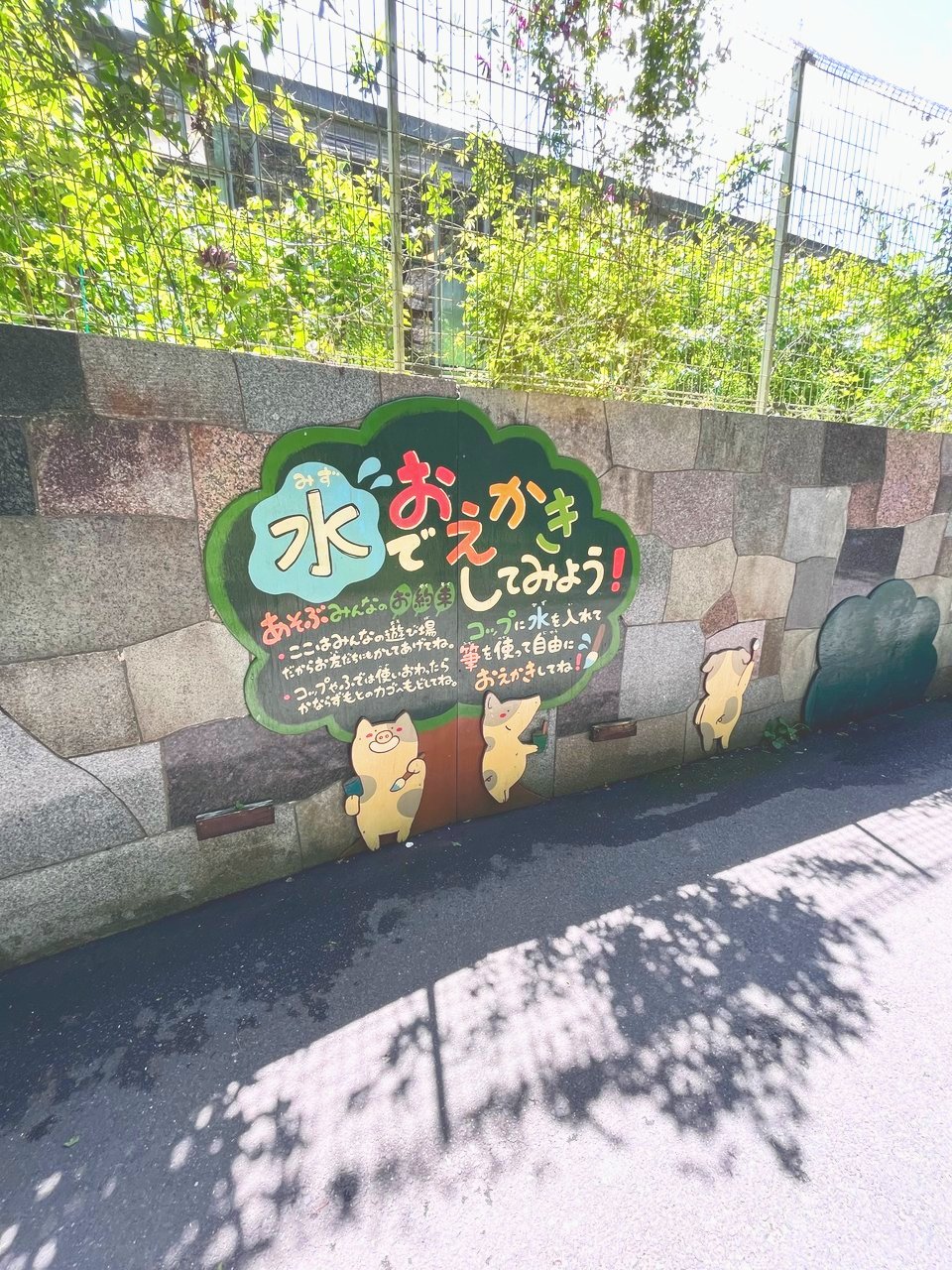 水でおえかきしてみよう、と書かれた石垣の看板