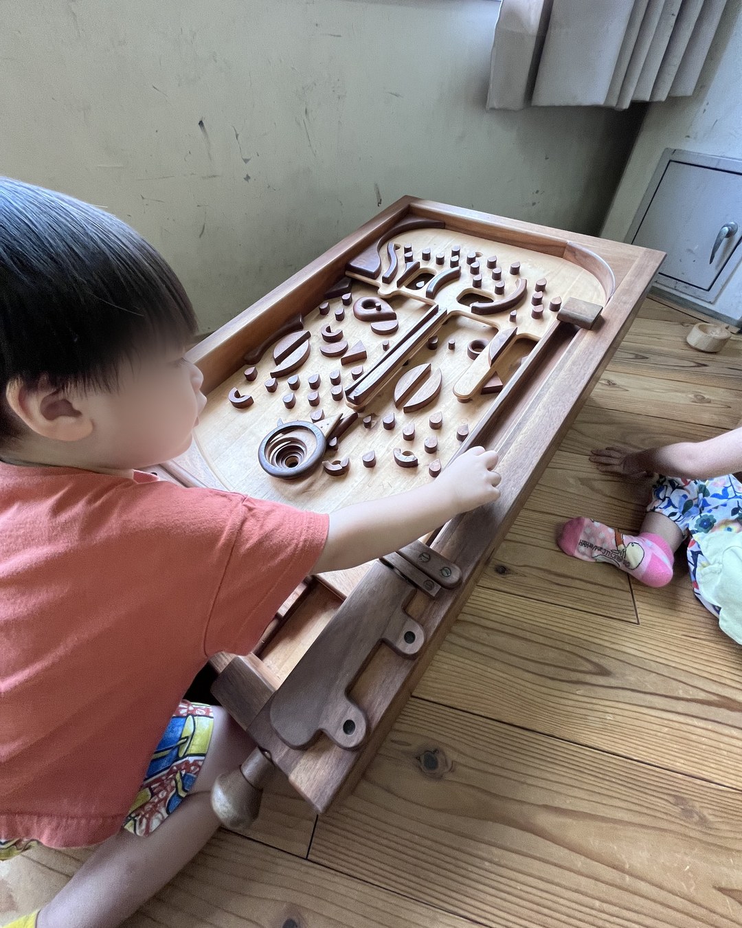 木製のピンボールのような台で遊ぶ子ども
