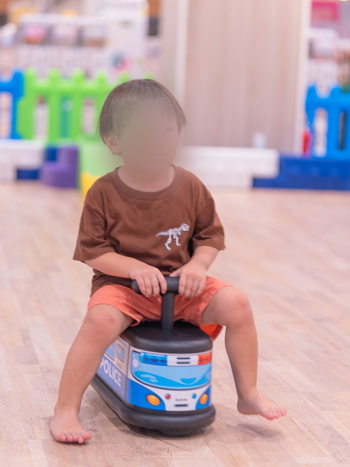 パトカーの形の乗り物にまたがる子ども