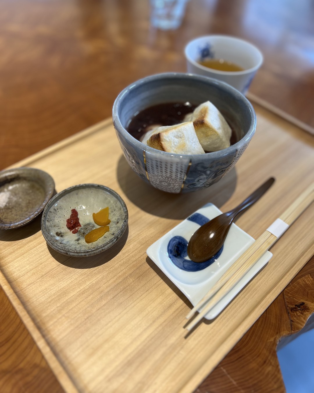 黒い器のぜんざいと小鉢がのったお盆