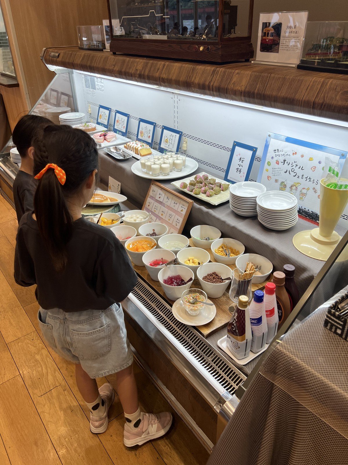「世界にひとつだけのオリジナルパフェを作ろう」のコーナーと、フルーツやトッピングが並ぶデザート台
