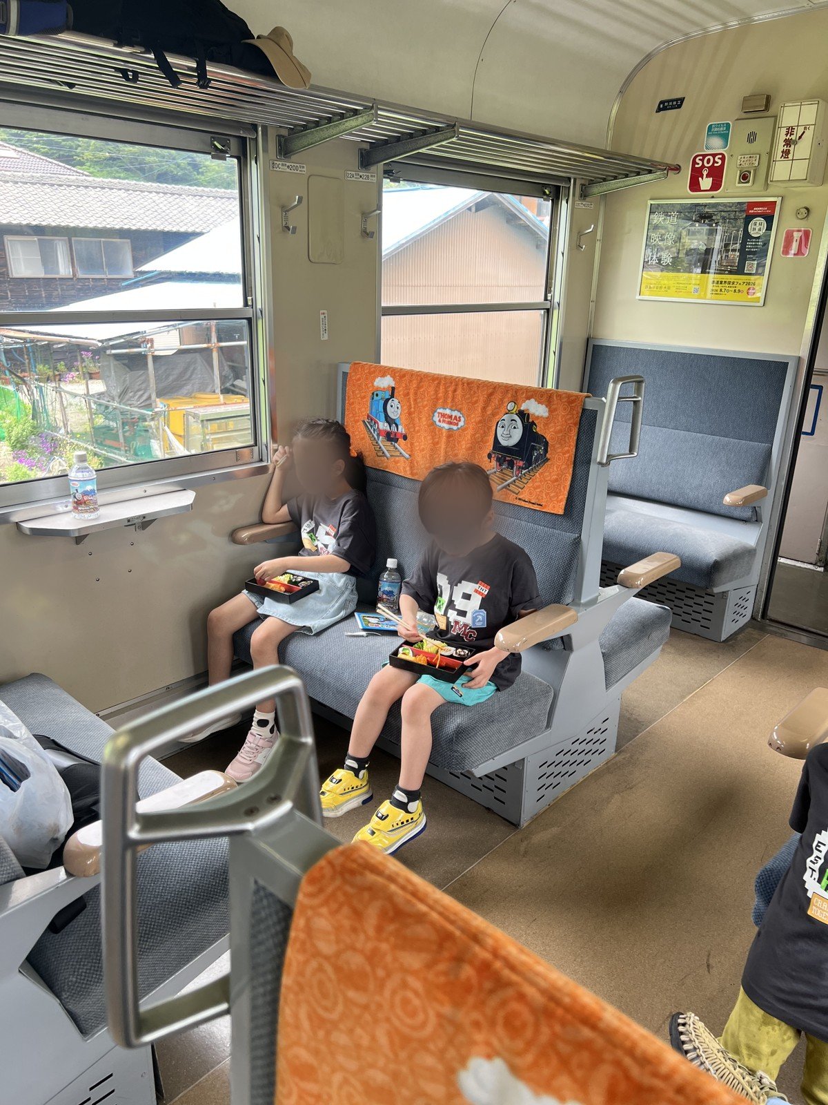 トーマスのカバーがかかった座席で、お弁当を食べる娘と息子