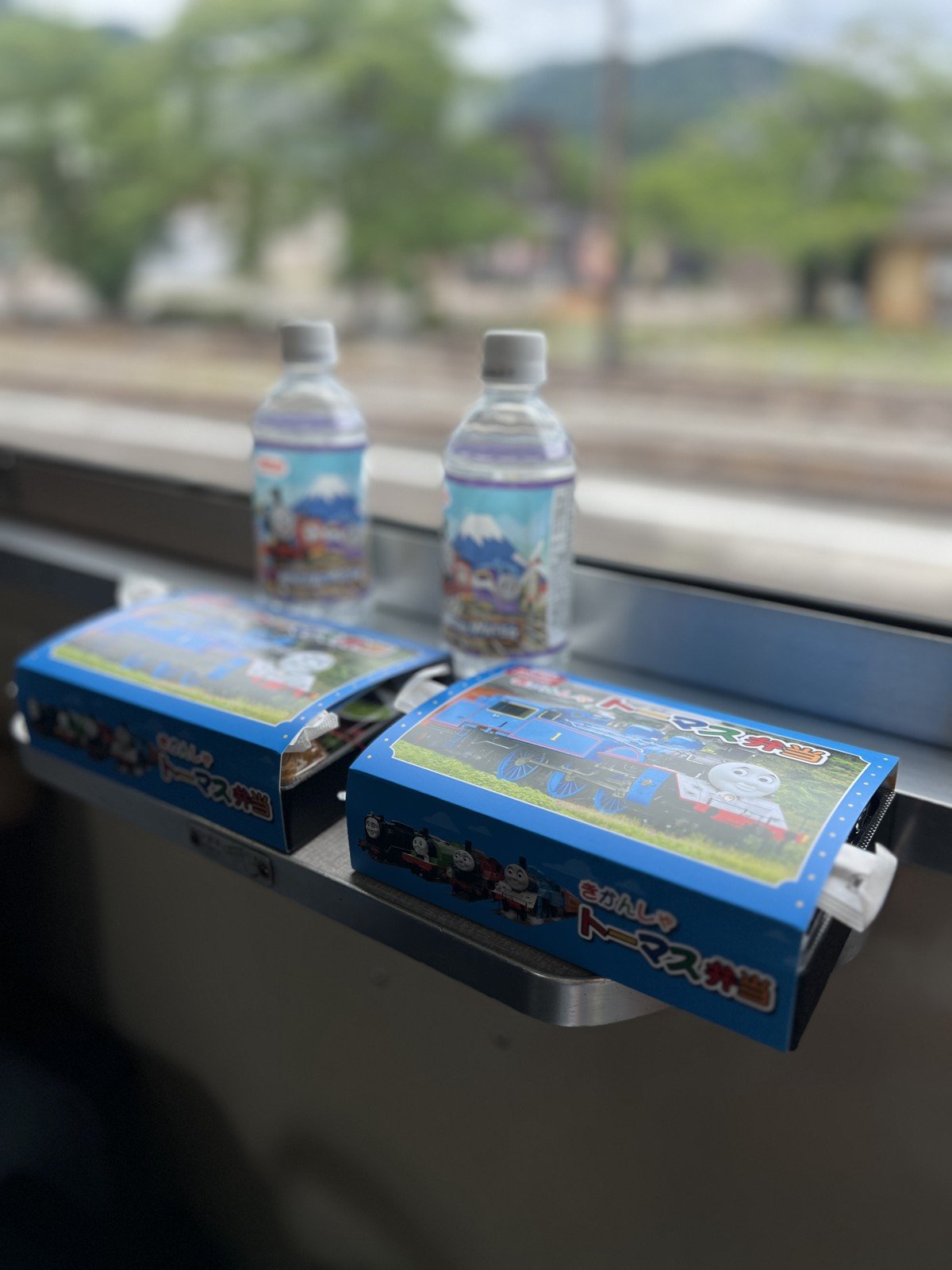 窓際に置いた「きかんしゃトーマス弁当」2つと、トーマスの絵の水