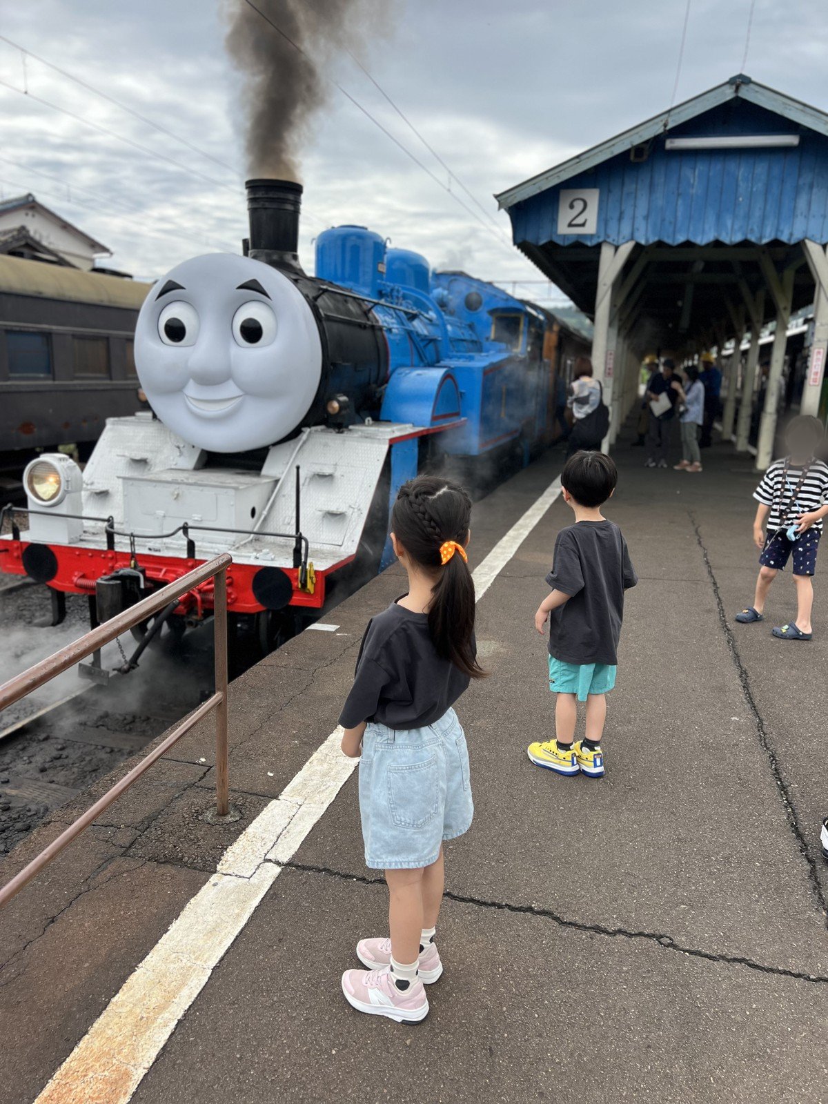 煙をあげるトーマス号を、ホームで見つめる娘と息子