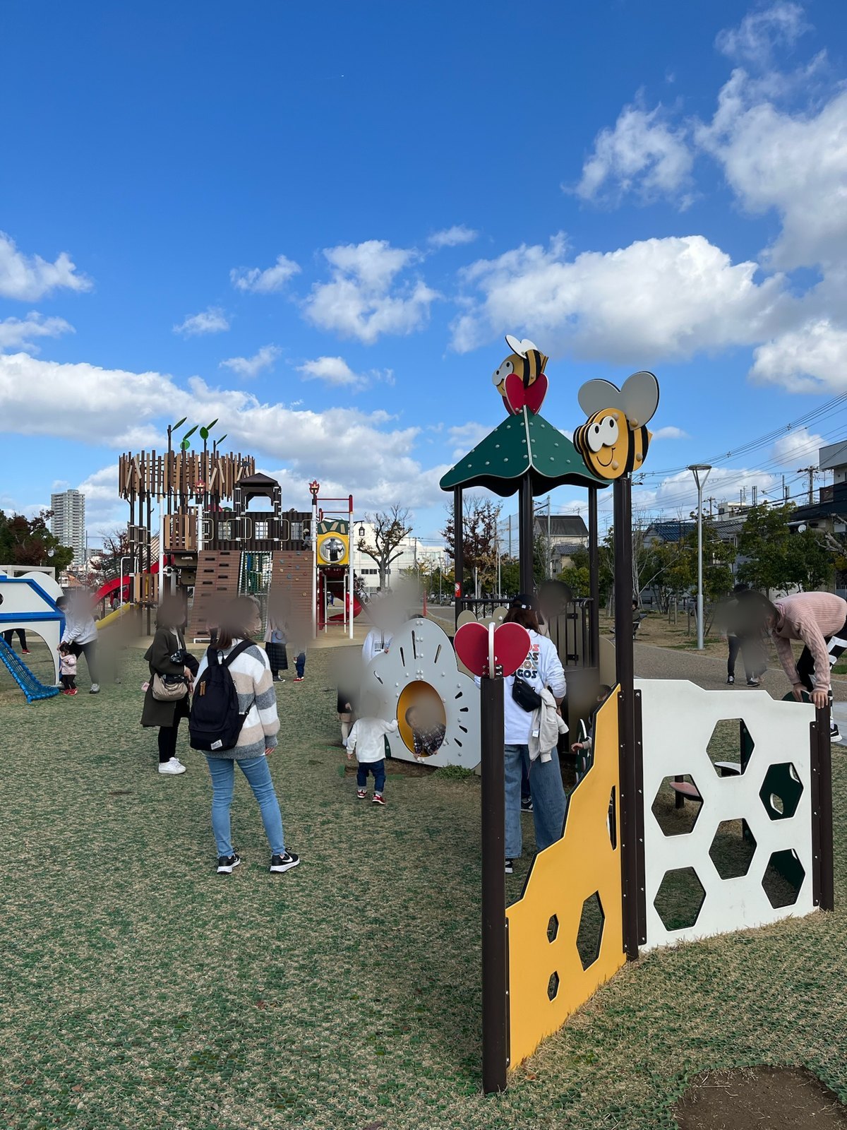 はちの飾りがついた小さい子向けの遊具で遊ぶ子どもたち。奥に大型遊具