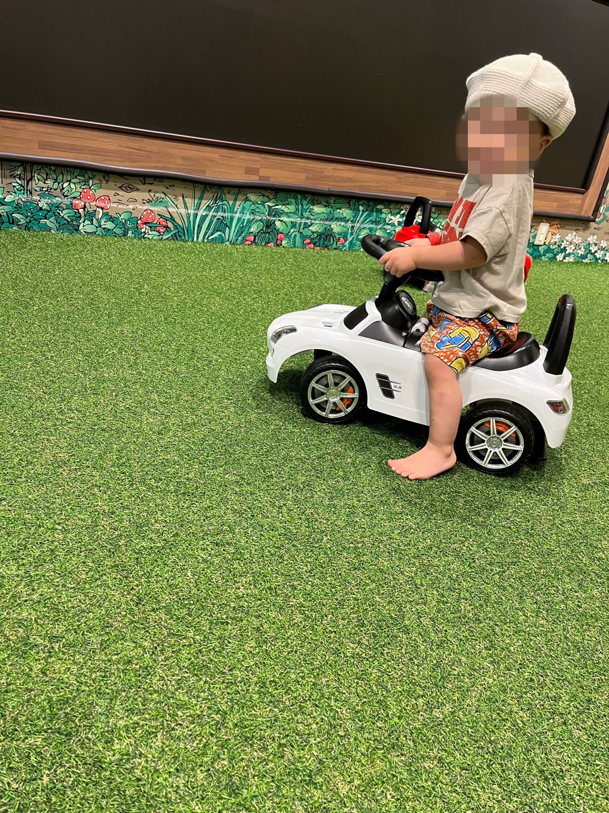 白い乗用玩具に乗る子ども