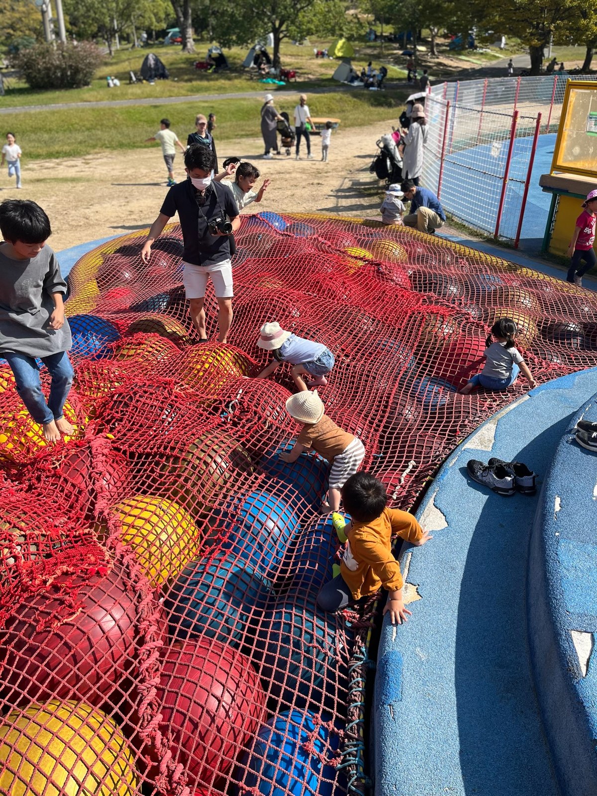 大きなカラーボールをネットで包んだ遊具の上を歩く子どもたち