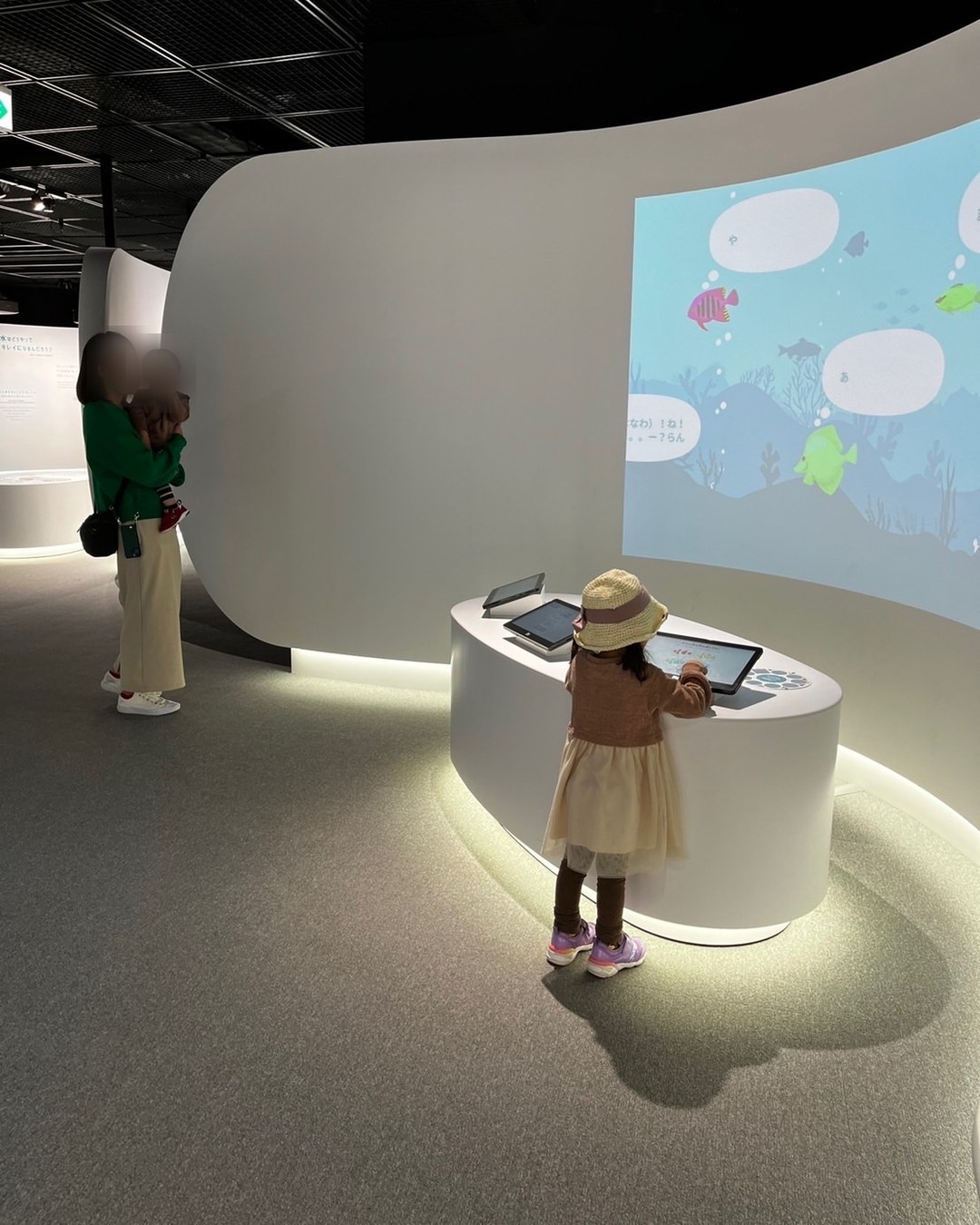 海の映像が広がる壁の前でタブレットを操作する子ども