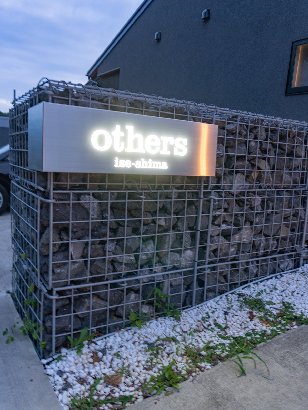 夜、ライトに照らされた「others」のサイン