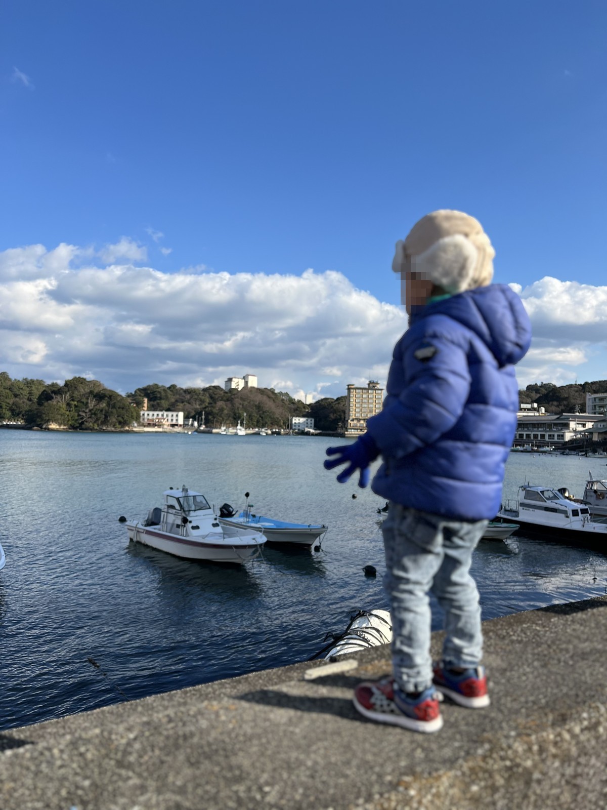 宿の前の海と停泊する船を眺める子ども
