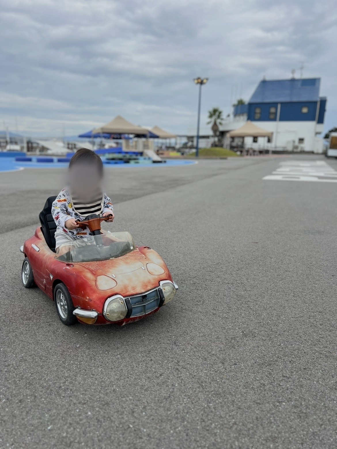 赤い車の乗り物遊具に乗る子ども