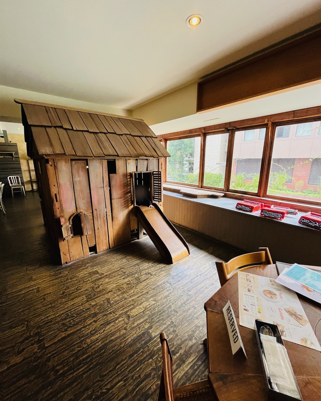 木の小屋に付いた滑り台と、窓辺に並ぶ赤いタイプライター