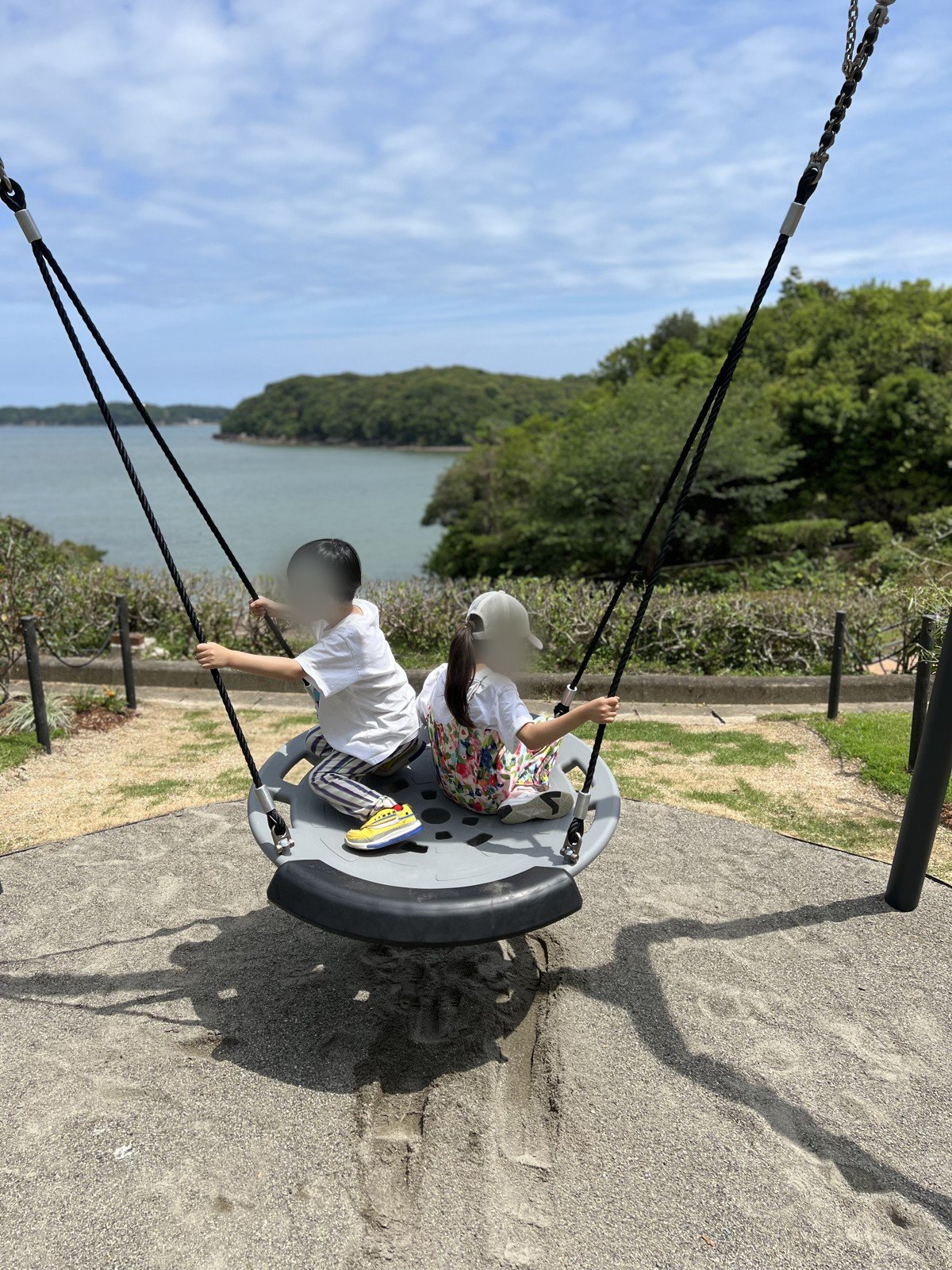 海を見下ろす丸いブランコに、きょうだいで乗る