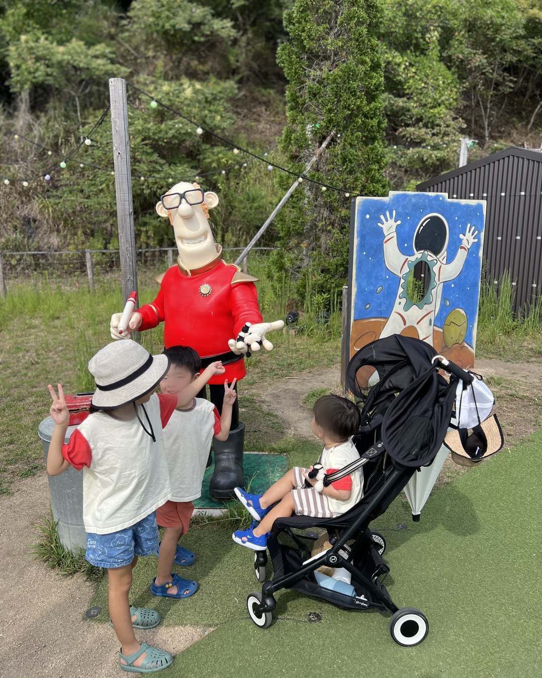 屋外に立つ赤い服の農夫の人形と子どもたち