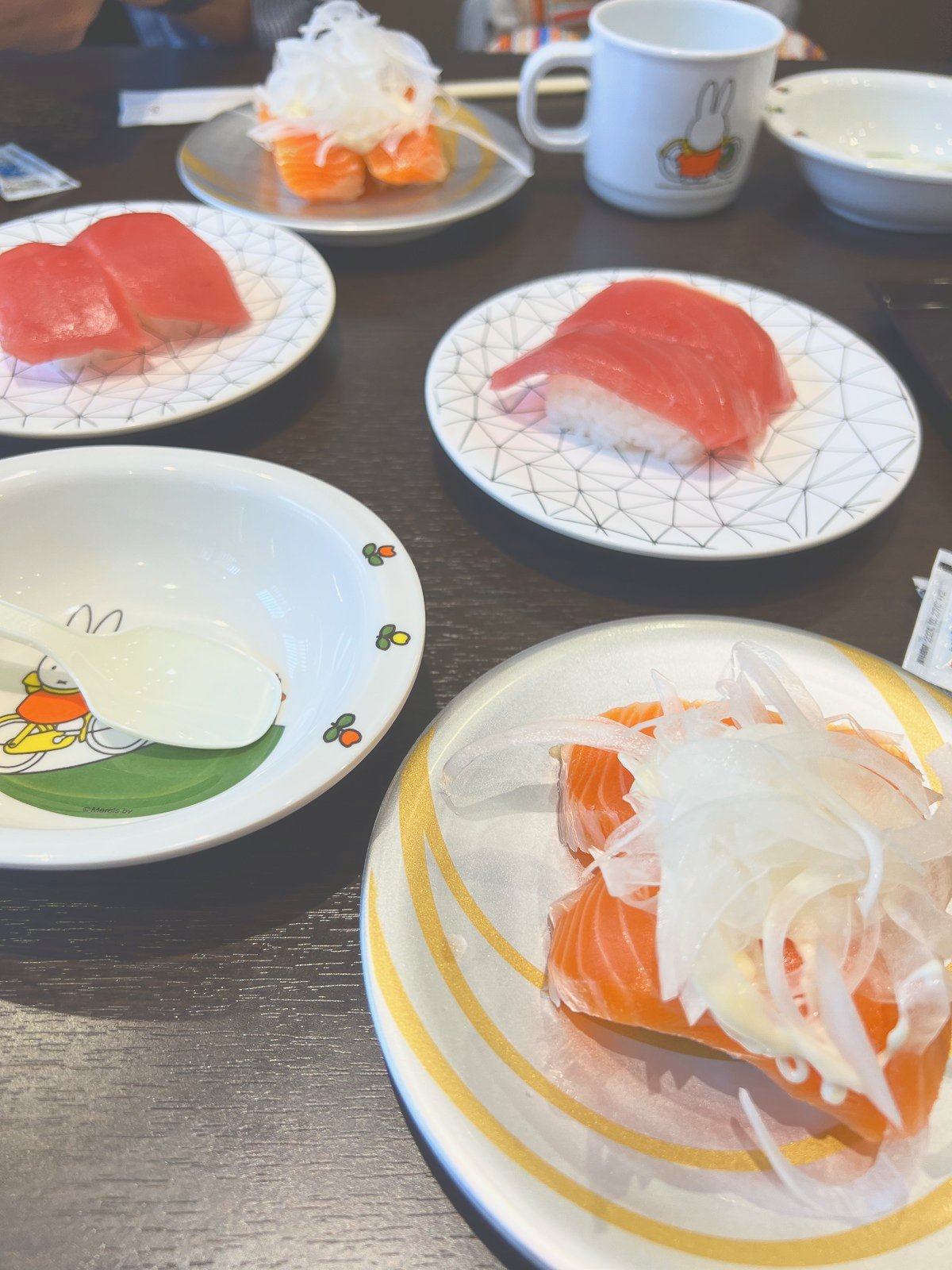まぐろやサーモンの寿司が並んだテーブルと、子ども用の食器