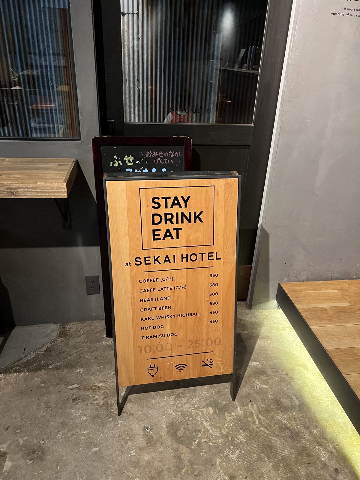 「STAY DRINK EAT at SEKAI HOTEL」と書かれた立て看板のメニュー