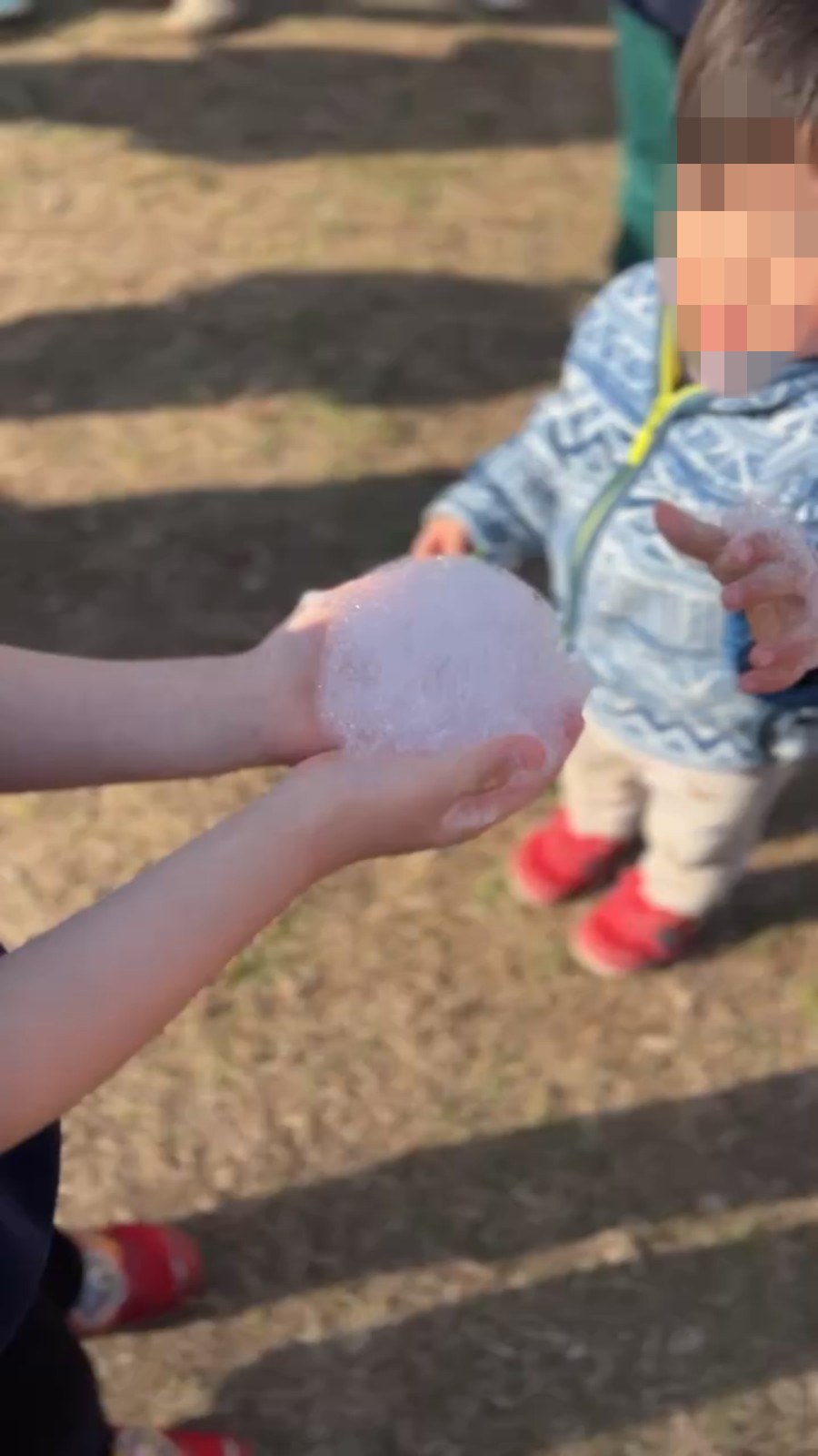 手のひらにのせたシャボン玉の泡を受け取る子ども