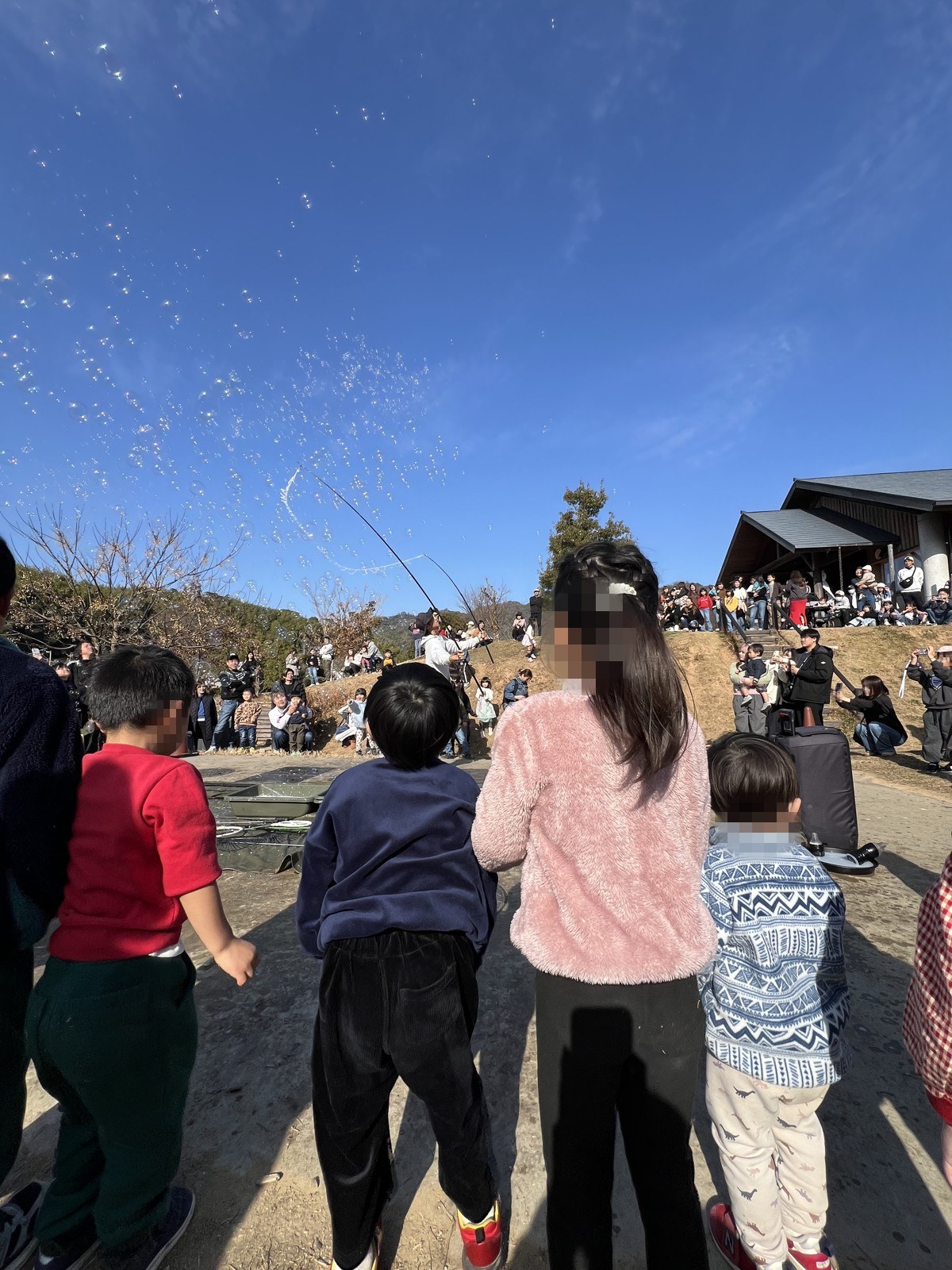 青空いっぱいに飛ぶシャボン玉と、それを見上げる人だかり
