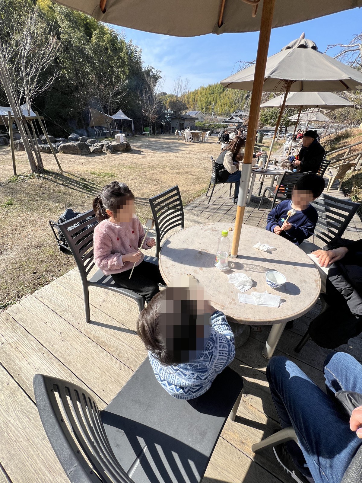 パラソルの下のテラス席で食事をする子どもたち
