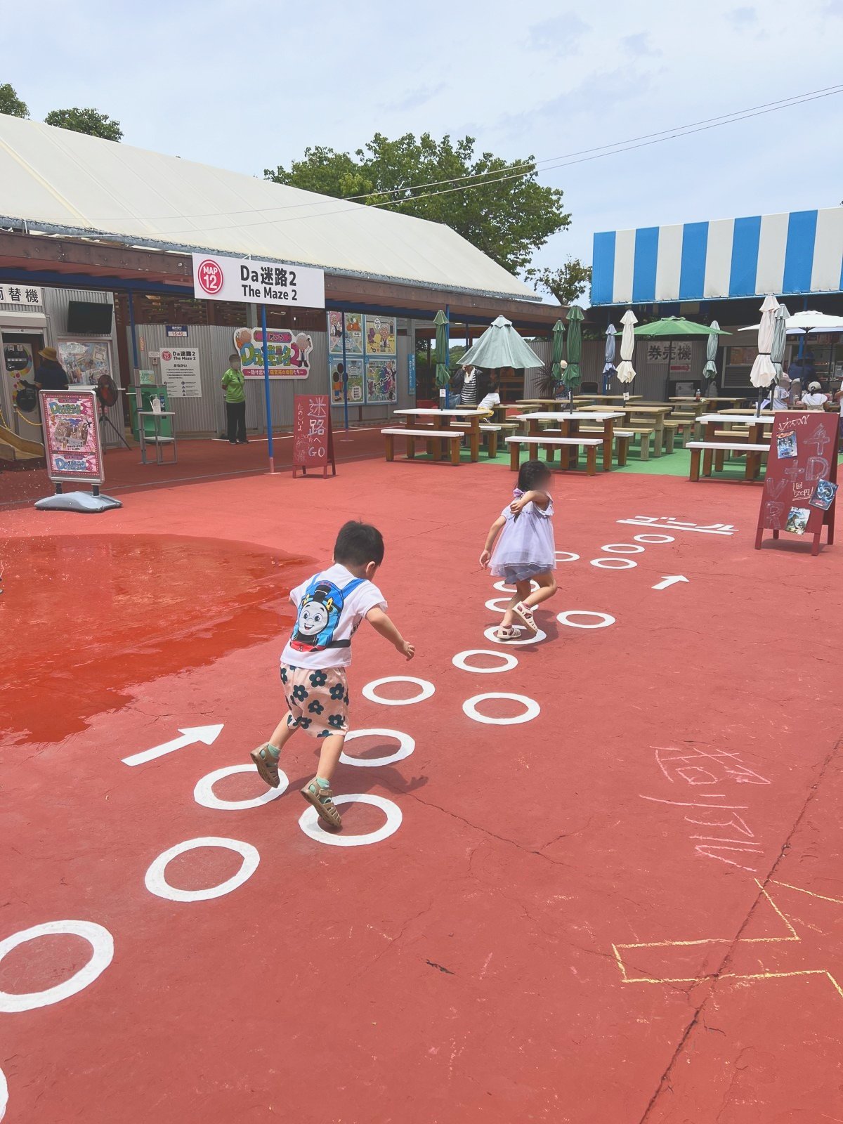 屋外の広場でケンケンパをする子どもたち