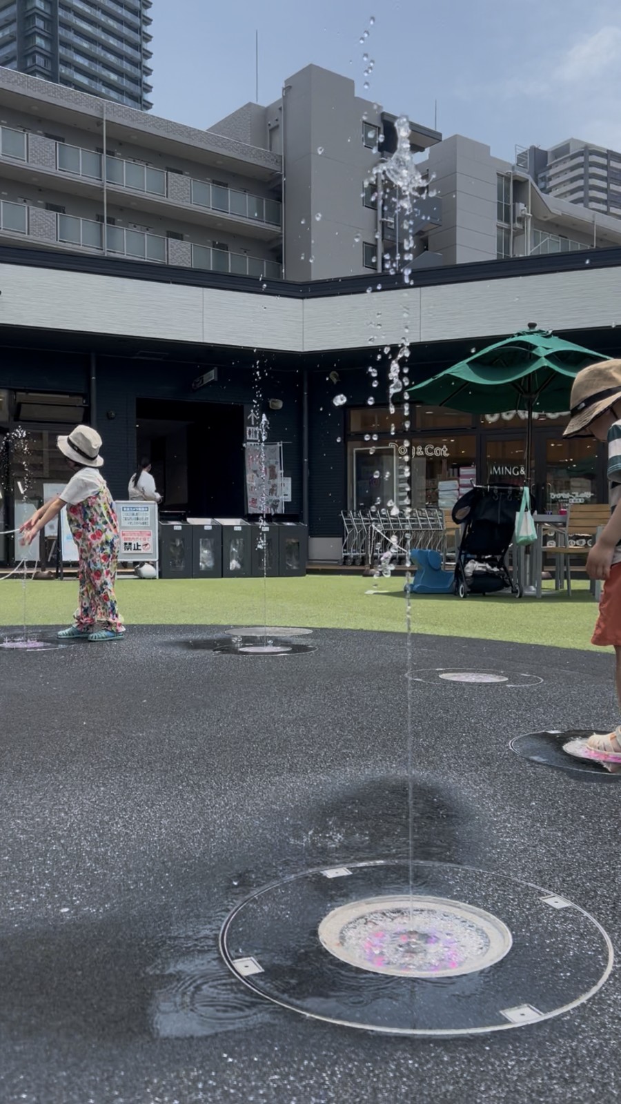 床から噴き上がる噴水で遊ぶ子ども