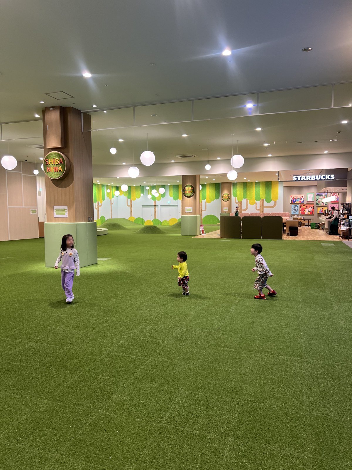 芝生の広場を走り回る子どもたち