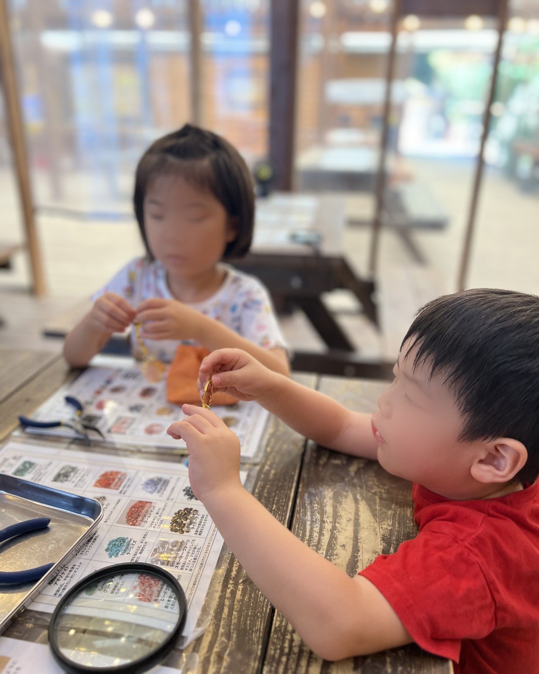 石の一覧表を見ながらアクセサリーを作る子どもたち